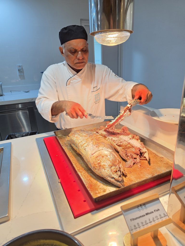Szakács Finhunumas Whole Fish ételt szeletel a pult mögött.